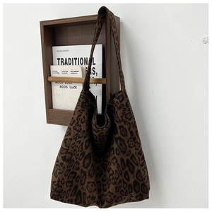Detail view of large leopard print tote bag hanging on a dark wood rack in minimalist scene