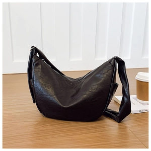 Detailed texture of black leather dumpling bag with silver zipper and wide strap