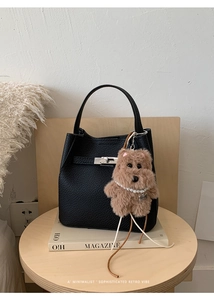 Detail of black pebbled leather bucket bag with silver turn-lock and dog charm