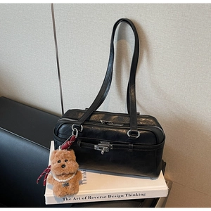 Detail of black vintage shoulder bag with silver clasp and cute plush bear charm
