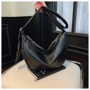 Detail of matte black crescent bag featuring soft PU leather texture and silver zipper