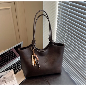 Detailed view of deep brown tote bag with vintage texture and wooden bead tassel ornament