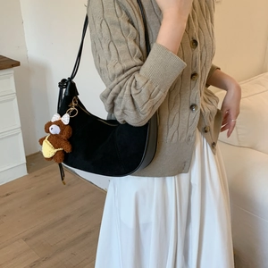 Detail of black suede hobo shoulder bag with a cute brown teddy bear plush charm