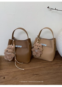 Close-up of litchi leather bucket bags with metal locks and plush dog charms