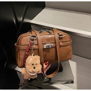 Detailed close-up of brown faux leather boston bag with silver lock and plush puppy charm