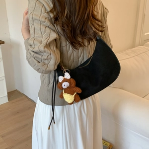 Detail of black suede hobo bag with fringe tassel and a cute plush bear pendant