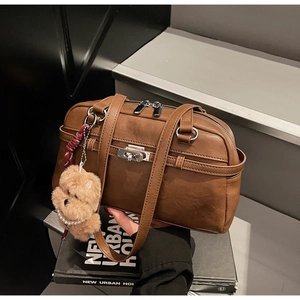 Detail of brown matte leather shoulder bag with silver hardware and plush bear charm