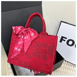 Détail du sac de mariage rouge en jacquard avec texture florale et foulard de囍