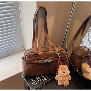 Detail of vintage brown leather bowling bag with silver buckle and plush bear charm