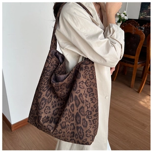 Detail of a large leopard print tote bag styled with a beige trench coat in a home setting