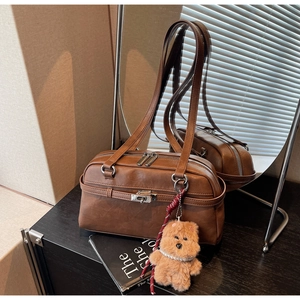 Detailed close-up of retro caramel leather bag with a cute bear charm and silver hardware