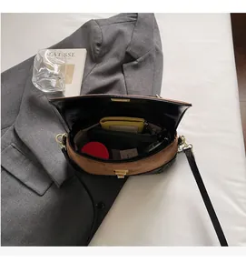 Detailansicht des geräumigen Innenlebens der zweifarbigen Satteltasche mit goldenem Schloss