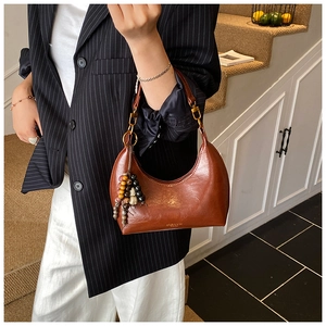 Détail du sac demi-lune en cuir ciré marron avec boucle dorée et pampilles à perles