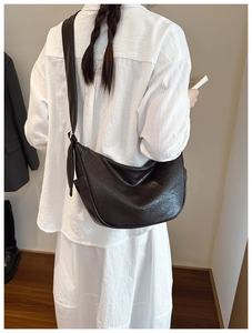 Detailed view of dark brown hobo bag with embossed logo and adjustable wide shoulder strap