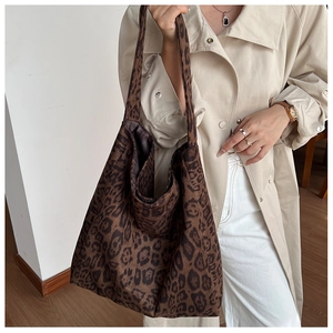 Close-up of leopard print tote bag fabric and wide shoulder strap on a beige trench coat