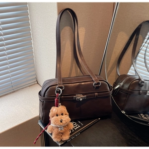 Detail of dark brown leather Boston bag with metal lock and plush dog accessory
