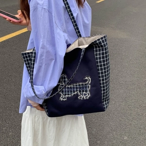 Détail d'un grand sac cabas en toile bleue avec des panneaux à carreaux et un motif de chien