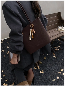 Dettaglio borsa tote in pelle opaca marrone scuro con nappa etnica di perline in legno