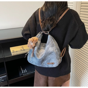 Detailed back view of a blue-grey washed leather tote bag with a plush dog charm