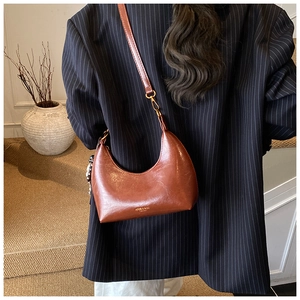 Détail d'un sac hobo marron vintage porté avec un blazer à rayures élégant et chic