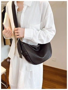 Detail of a black crescent crossbody bag with textured leather and wide shoulder strap