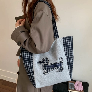 Grand sac cabas en toile à carreaux avec écusson teckel brodé porté sur un trench-coat