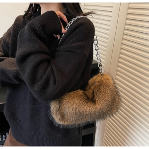 Sac à bandoulière en fausse fourrure marron avec chaîne argentée porté par un mannequin