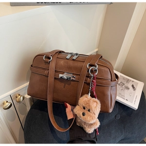 Brown vintage leather handbag detail with silver lock and plush puppy charm on seat