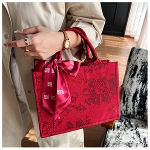 Gros plan d'un sac à main rouge de mariée en jacquard fleuri avec ruban traditionnel