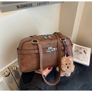 Detailed view of a vintage brown leather pillow bag with a plush dog charm and silver clasp