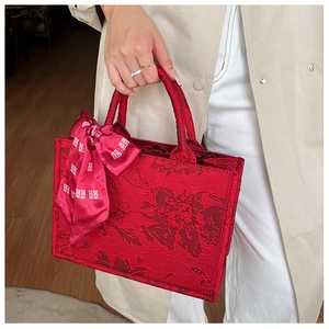 Détail du sac à main de mariée rouge avec motif jacquard floral et ruban en soie festif