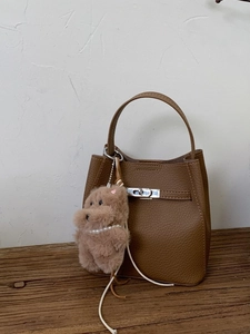 Brown lychee leather bucket bag with silver twist lock and plush puppy charm