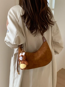 Brown faux suede crescent bag with a cute bear charm shown on a stylish model