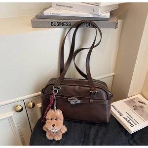 Detail of vintage dark brown shoulder bag with silver lock and plush puppy charm accessory