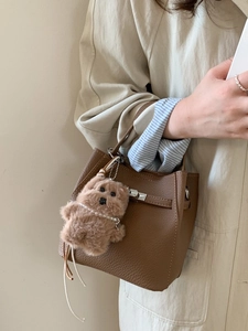 Brown litchi leather bucket handbag featuring a silver lock and cute bear charm pendant