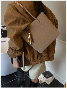 Dettaglio borsa tote vintage in pelle opaca con ciondolo in legno e tracolla lunga