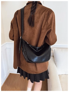 Detail of black leather crescent bag with embossed logo and wide comfortable shoulder strap
