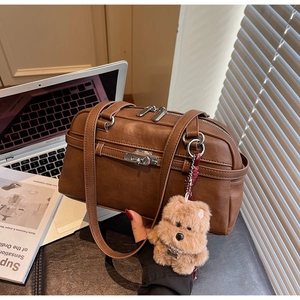 Detailed close-up of brown vintage leather pillow bag with silver buckle and bear charm