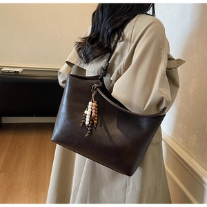 Detail of dark brown tote bag with colorful wooden bead tassel and knotted shoulder strap