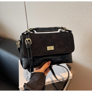 Detail einer matt schwarzen Stepptasche mit goldenem Drehverschluss und Ledergriff