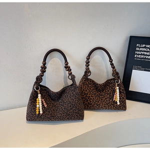 Detail von Leopard-Taschen mit runden Holzperlengriffen und dekorativem Quastenanhänger