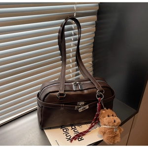 Detail of vintage brown shoulder bag with silver double zippers and plush dog charm