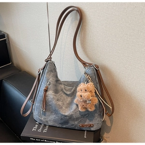 Detail of grey washed canvas tote bag with leather straps and brown plush animal charm