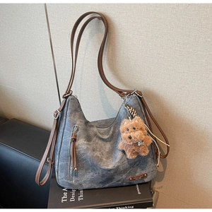Detail of grey hobo bag with brown leather straps and a cute brown plush dog pendant