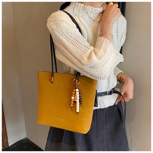 Dettaglio della borsa tote in pelle gialla opaca con perline di legno e tracolla