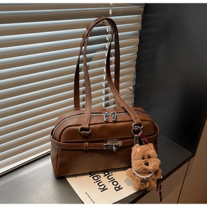 Detail of vintage brown shoulder bag with silver hardware and cute plush dog charm