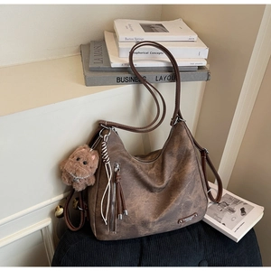 Detail view of vintage brown tote bag with metal logo, decorative zipper and bear charm