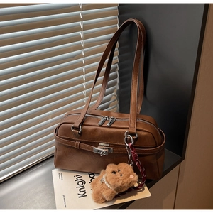 Detail of vintage brown leather boston bag with metal lock and cute bear charm
