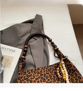 Detail der Retro-Leoparden-Tote mit rustikalem Holzperlengriff und schicken Anhängern