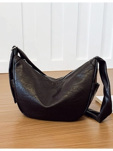 Minimalist black crescent shoulder bag in soft wrinkled leather with silver zipper